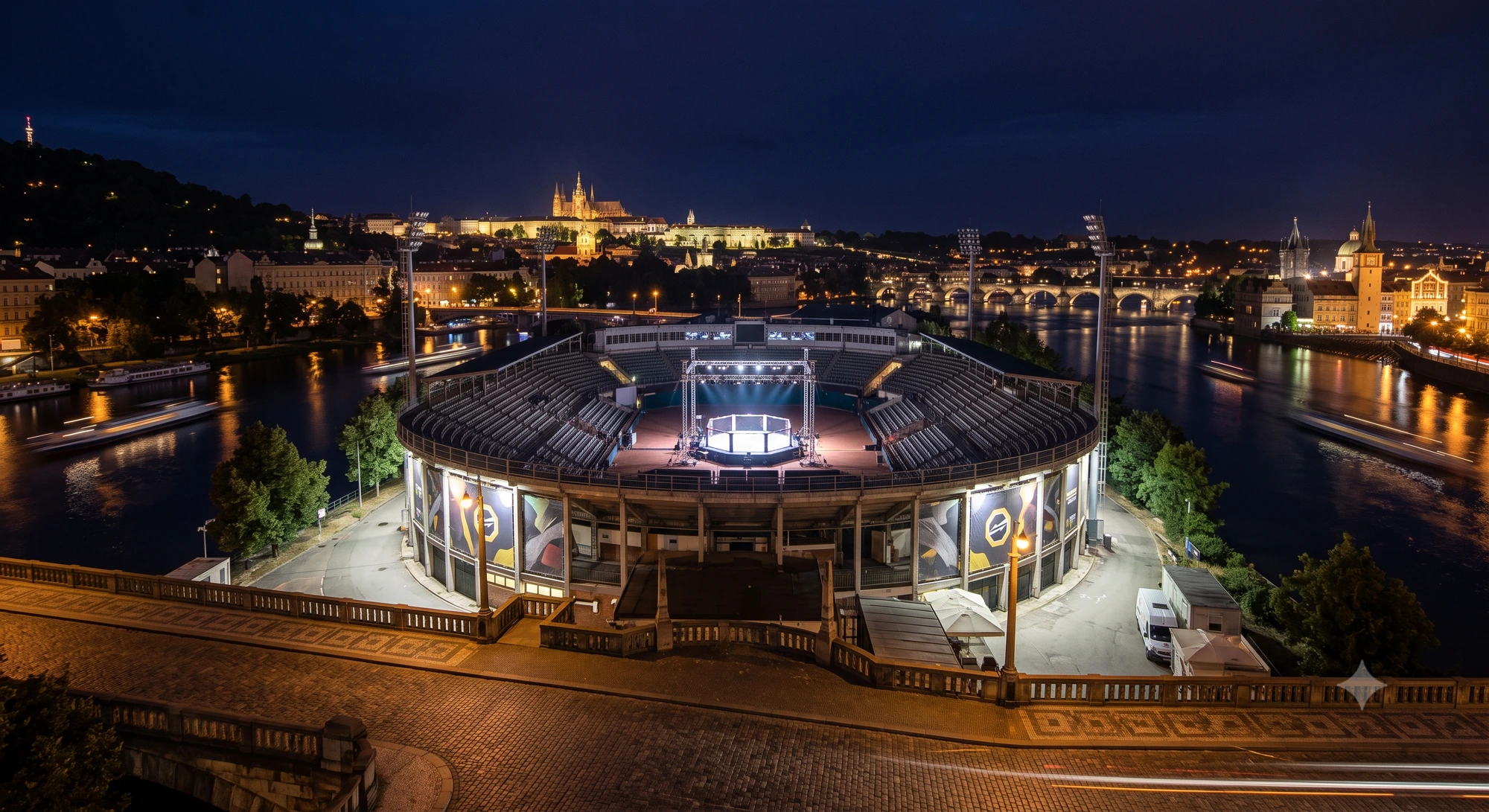 The OKTAGON cage set up at Štvanice Island in central Prague, with the Vltava river and Prague Castle in the background — the venue for OKTAGON 92 on August 1, 2026