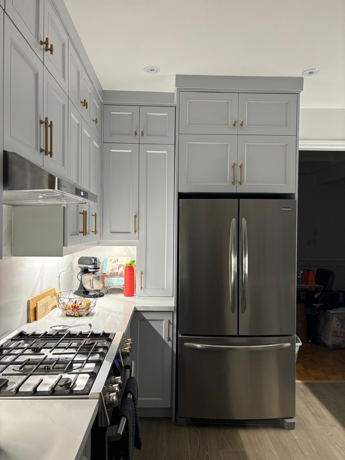 Custom grey kitchen cabinets with brass hardware built by Hive Interior
