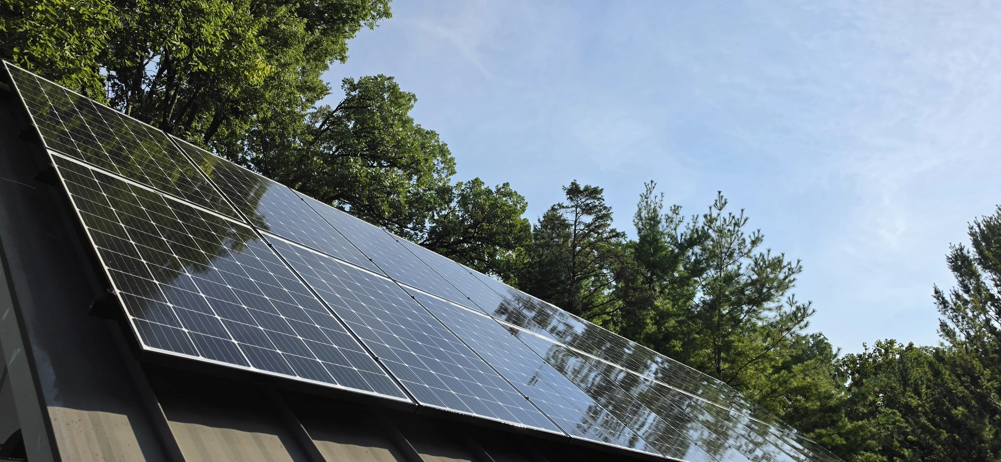 Same Southern Wisconsin residential solar array on a standing-seam metal roof photographed at 9:22 AM after Solar Alchemist cleaning — the glass is dark, uniform, and mirror-clean