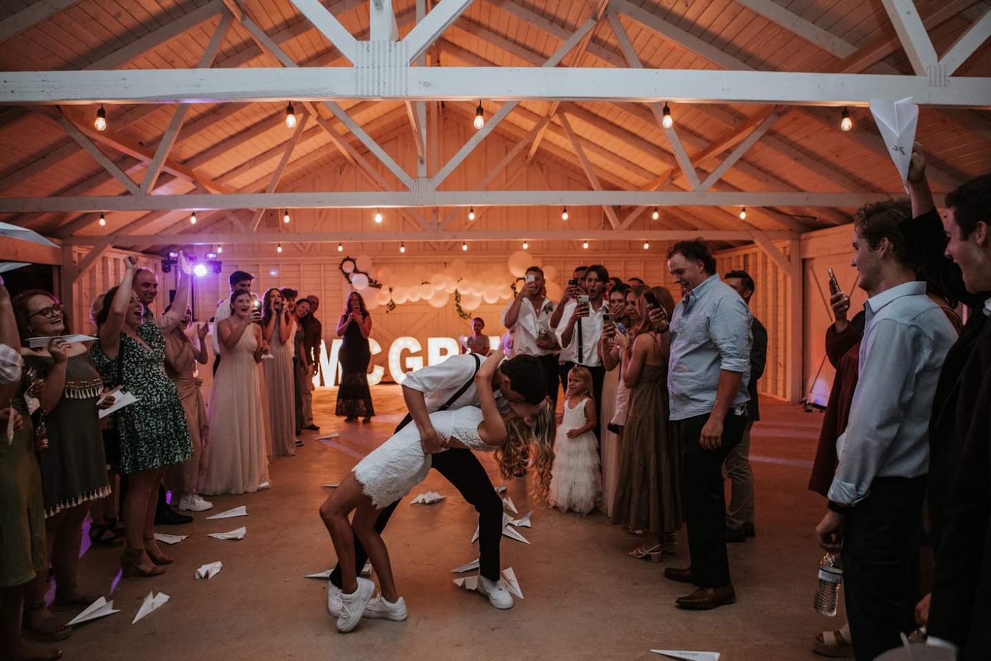 Bride and groom first dance surrounded by cheering guests