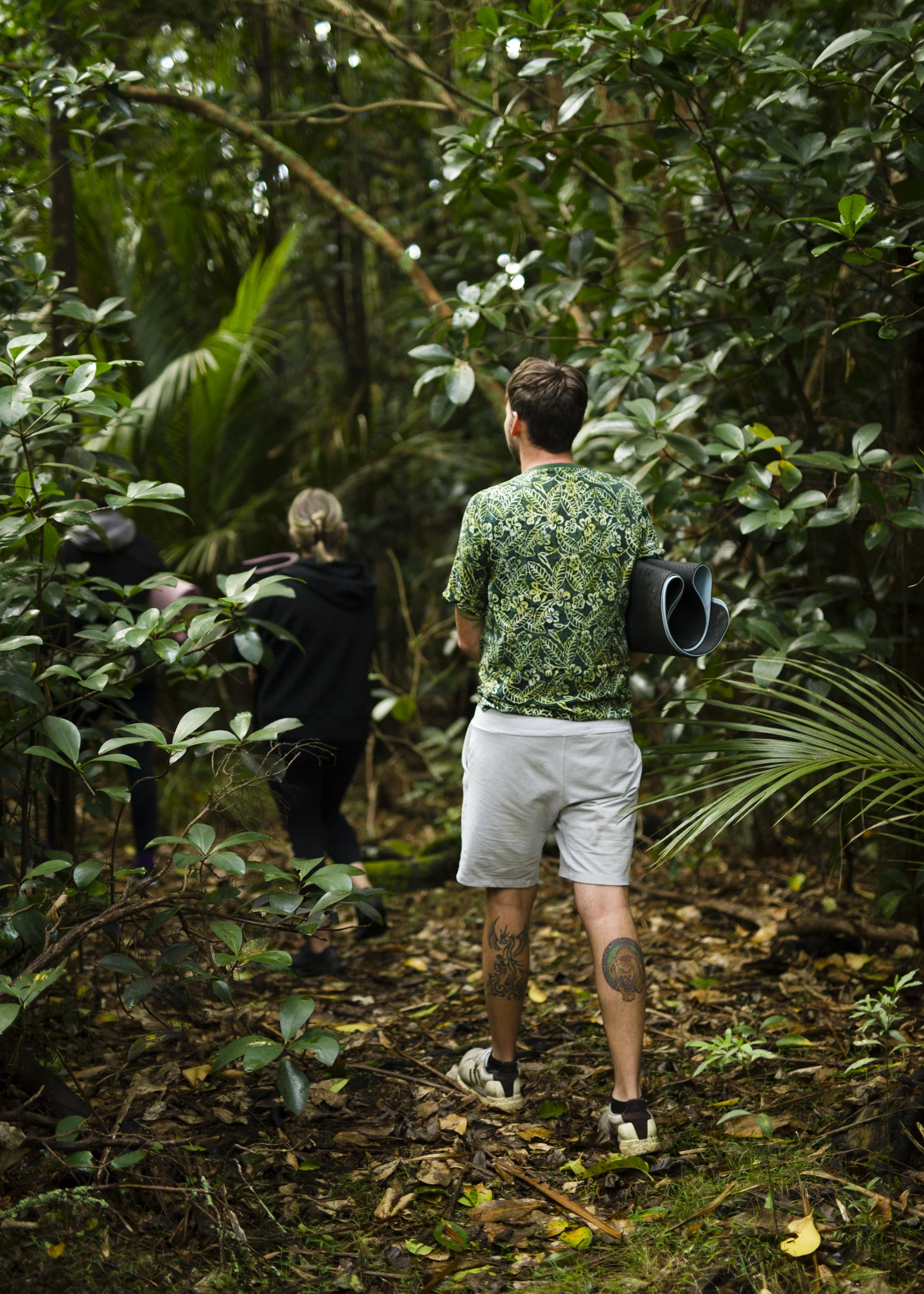A small team walking quietly through native forest with their mats