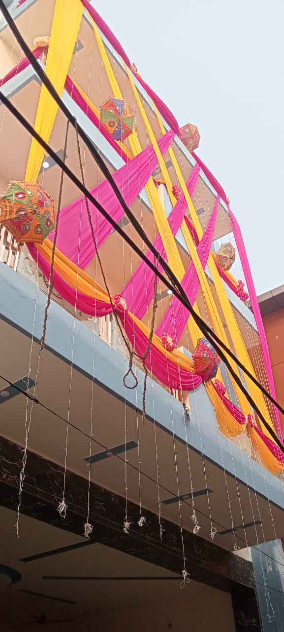 Building decorated with bright pink and yellow drapes and festive ornaments